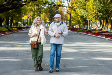 Obraz premium Elderly beautiful married couple on a walk in an autumn park