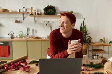 A young man enjoys a warm drink while preparing for a cheerful Christmas celebration.
