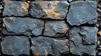 Obraz premium A close-up of a stone wall, showing rough-hewn, irregular, gray stones with some orange/brown weathering.