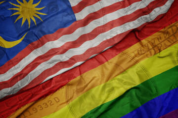 Obraz premium waving colorful flag of malaysia and gay rainbow flag on the dollar money background. finance concept