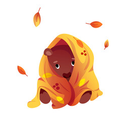 A cute little bear sits wrapped in a warm yellow blanket.