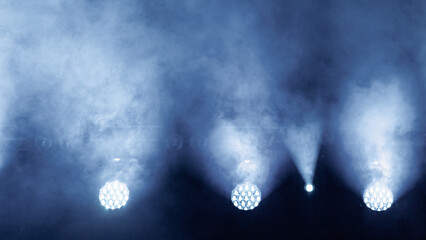 Rays of light from white spotlights on stage, close-up, in concert haze of fog machine, no people