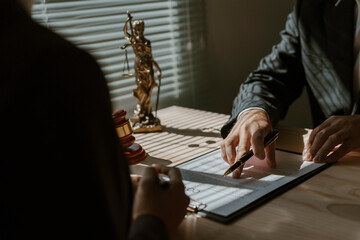 Lawyer pointing at contract details with pen, explaining agreement terms to client during office...