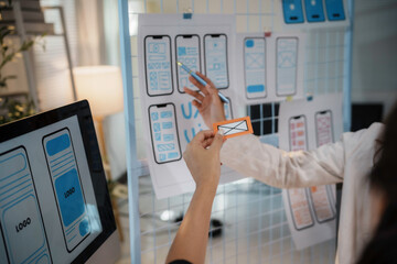 Web designers improving ux and ui of mobile app during a meeting, adding new features and...