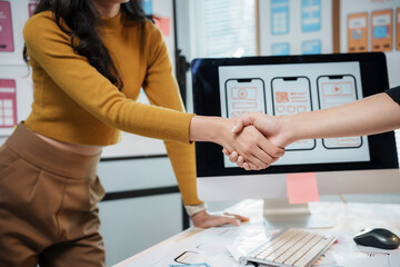 Two ux ui designers shaking hands after successfully developing a mobile application