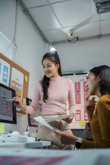 Obraz premium Two female web designers are discussing the user interface of a mobile application, working together in their office