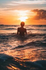 Fototapeta premium An individual is seen enjoying the ocean waves at sunset, bathed in warm golden light.