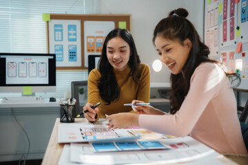 Two female ux designers collaborating on wireframes for a mobile application, discussing user...