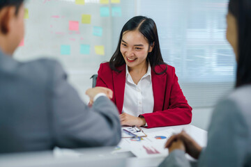 Asian businesswoman shaking hands with business partner after successful meeting in modern office