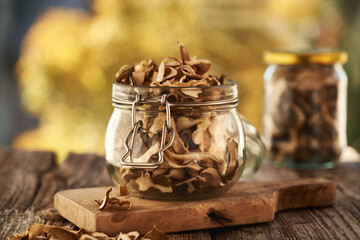 Dried wild king bolete or porcini mushrooms in glass jars on a table outdoors