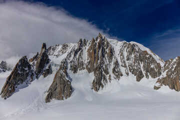 Snow covered mountains and rocky peaks of the Alps from the sky way between Chamonix and Courmayeur in Italy and France Alps. Dent du Gigante rocky towering peak and glacier at the bottom of Montblanc