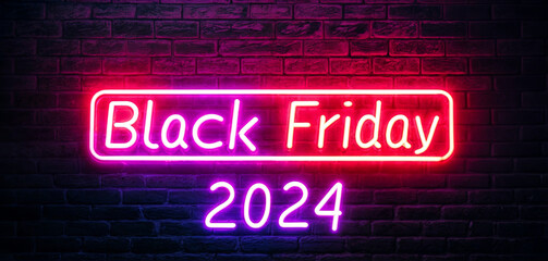Obraz premium A bright neon sign illuminates the words Black Friday 2024 in pink and purple against a dark brick wall, promoting upcoming shopping events in a lively urban atmosphere