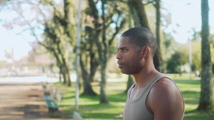 Determined African American man walking in a public park on a sunny day. Focused male in athletic wear, moving confidently while the camera circles around him outdoors