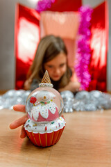 Cute little girl playing inside a big christmas gift box with a snow ball
