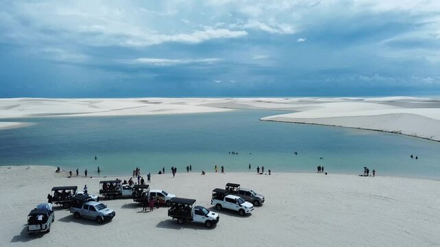 A drone reveals the vast white dunes of Len&ccedil;&oacute;is Maranhenses, with shimmering lagoons nestled between the rolling sands. The sweeping aerial view captures the stunning contrast of the endle