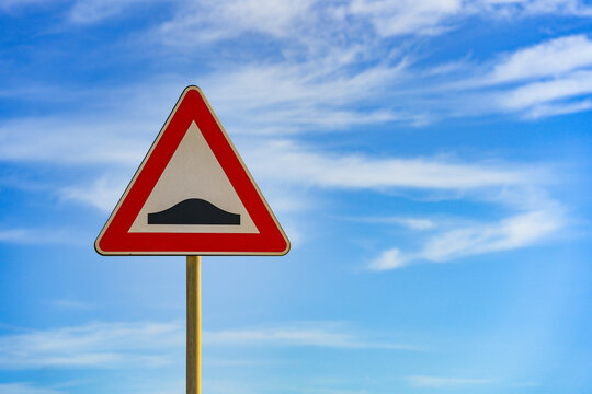 Red and white triangular warning road sign with a warning of a bumpy road ahead concept against a clear blue sky background