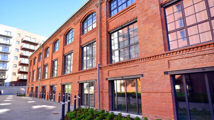 Fototapeta premium Modern loft building from red brick in downtown area. Industrial design in city architecture. Business concept.