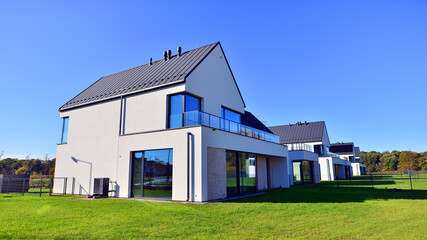 Obraz premium New elegant modern single family house. Terraced family homes in newly developed housing estate. Facade of a modern house with white walls. Real estate concept, european style. 