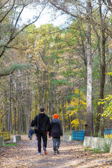 Fototapeta premium a man and a child walk in an autumn park with tall trees