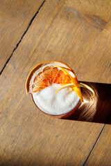 An orange-colored alcoholic cocktail served in a wide glass, garnished with a dried orange slice, fresh zest, and a gummy bear. The festive look makes it perfect for Christmas or New Year's celebratio