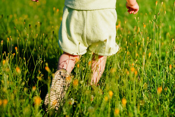 Caucasian joyful Little child girl runs on the green grass in the park in summer, the concept of a carefree childhood and freedom.