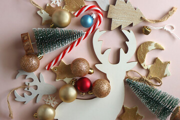 Various cute Christmas ornaments on pale pink background. Flat lay.