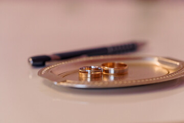 Elegant Wedding Rings on a Decorative Silver Tray with a Pen