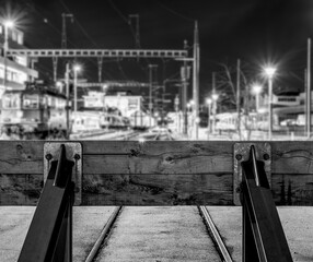 Obraz premium Buffer stop from behind. In front of the buffer stop lights, locomotives, and signals can be seen blurry in the distance. Low depth of field.