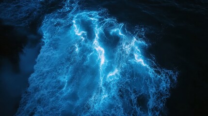 Bioluminescent waves glow in vivid neon blue as microscopic organisms light up in the dark, creating a surreal and mesmerizing effect across the ocean surface.
