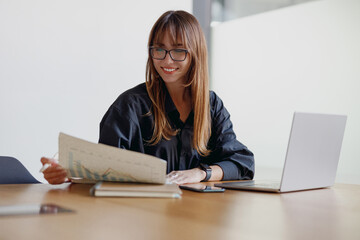 A dedicated professional woman meticulously reviews detailed financial charts in a modern contemporary workspace