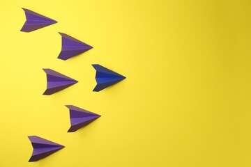 Handmade paper planes on yellow background, top view. Space for text
