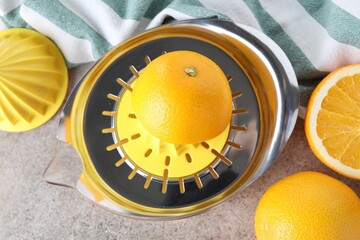 Metal juicer and oranges on grey table, top view