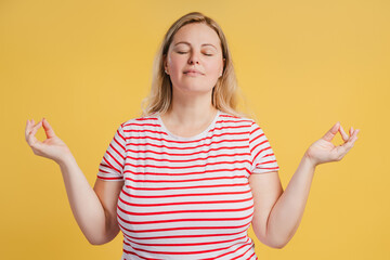 Young woman wearing casual striped t shirt doing meditation gesture with fingers