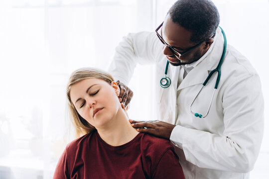 Young woman with neck pain is being examined by male physiatrist