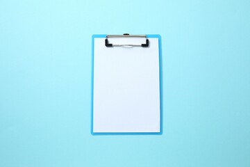 Clipboard with paper sheet on blue background, top view. Space for text