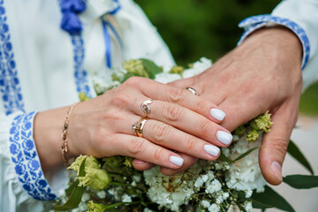 Fototapeta premium Elegant Wedding Rings on Hands Surrounded by a Delicate Floral Bouquet