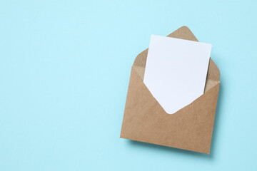 Сraft paper envelope and white card on color background with empty space