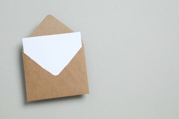 Сraft paper envelope and white card on gray background with empty space