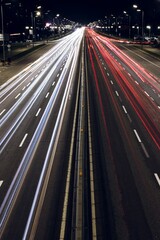 High-angle nighttime shot of a busy highway captured with long exposure. Red and white light trails from fast-moving cars create dynamic streaks under streetlights, highlighting the energy of urban