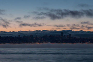 Naklejka premium Captivating Dawn Over City Skyline with Fog and Clouds: A Serene Urban Landscape