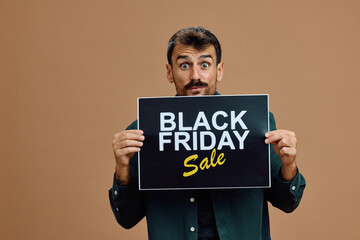 Studio shot of shocked man holding Black Friday sale placard looking at camera.