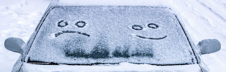 the sad and the happy smile on the snowy windshield of a car