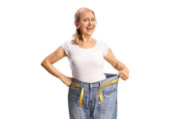 Fototapeta premium Happy mature woman trying on a pair of jeans, weight loss concept