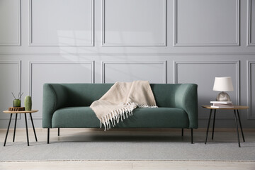 Comfortable sofa and side tables near grey wall in room