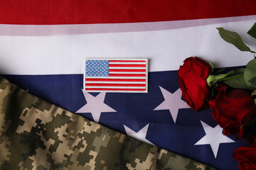 Veterans day. USA army patch, rose flowers and military uniform on American flag, flat lay
