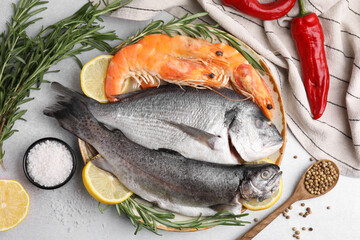 Different fresh sea food with spices on light grey table, flat lay