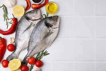 Sea food. Fresh raw fish and products on white tiled table, flat lay. Space for text