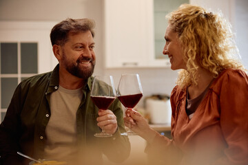 Happy couple toasting with wine during dinner at dining table.