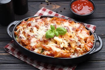 Delicious al forno pasta in baking dish on wooden table, closeup