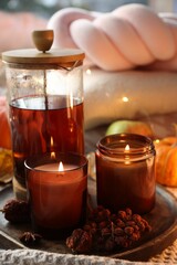 Burning candles, freshly brewed tea and autumn decor on fabric